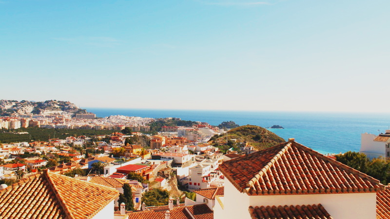 Utsikt over hustak med tegelpannor mot havet i Almunecar